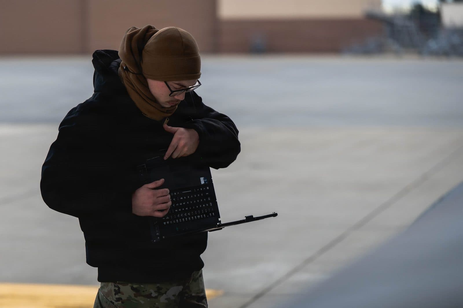 U.S. Air Force maintainer consults technical data on a ruggedized laptop beside a C-17 on the flightline